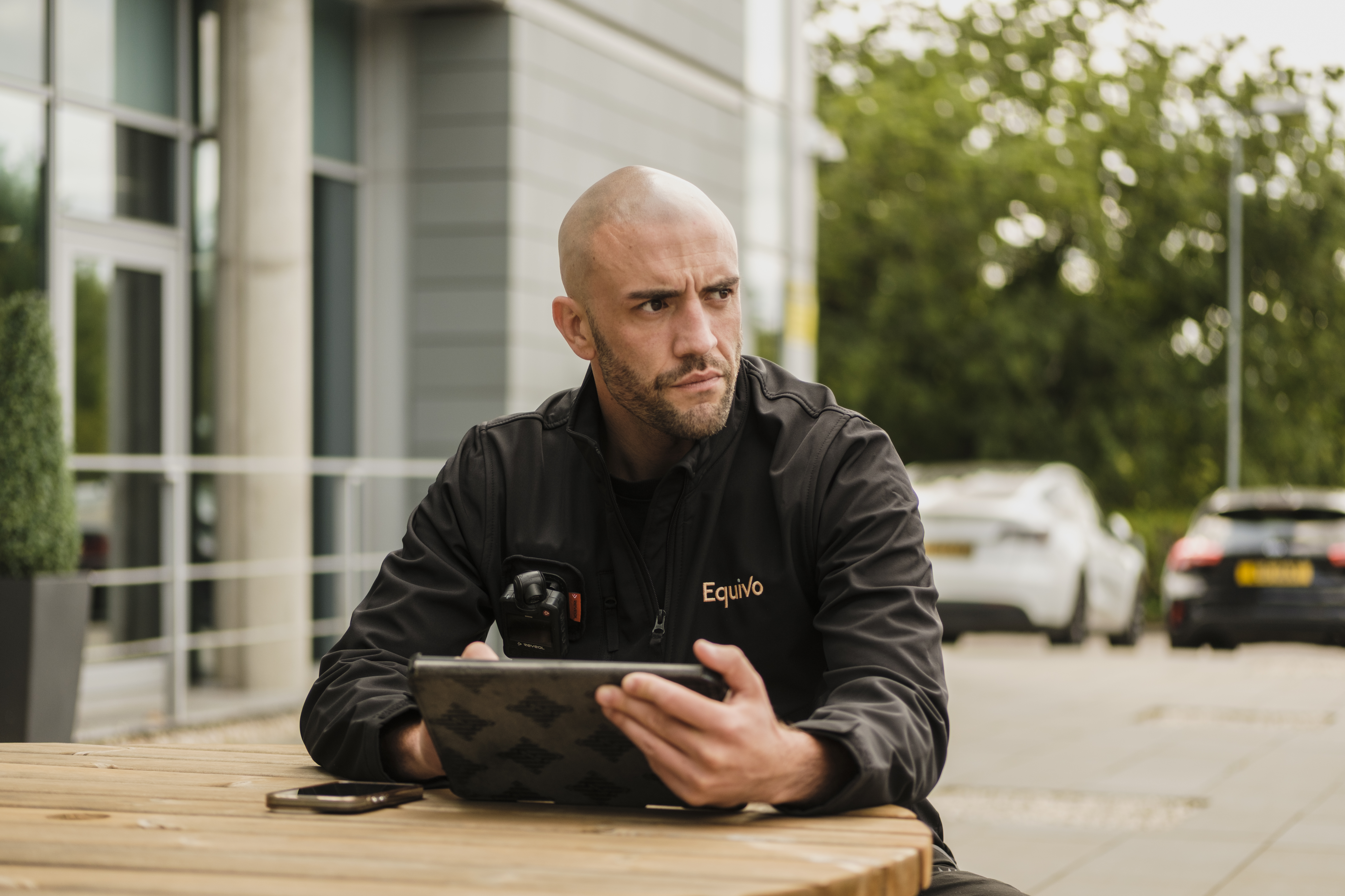 Agent managing commercial rent arrears recovery using iPad in office parking lot.