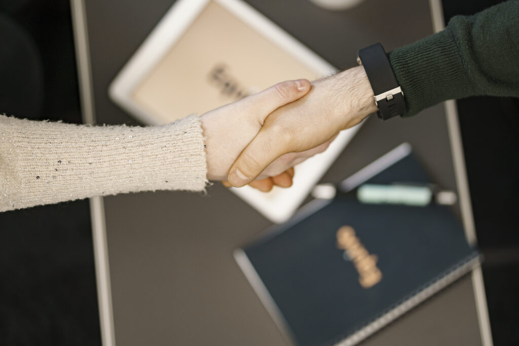 wo professionals shaking hands over Equivo-branded notepads and iPad, representing employment tribunal award resolution