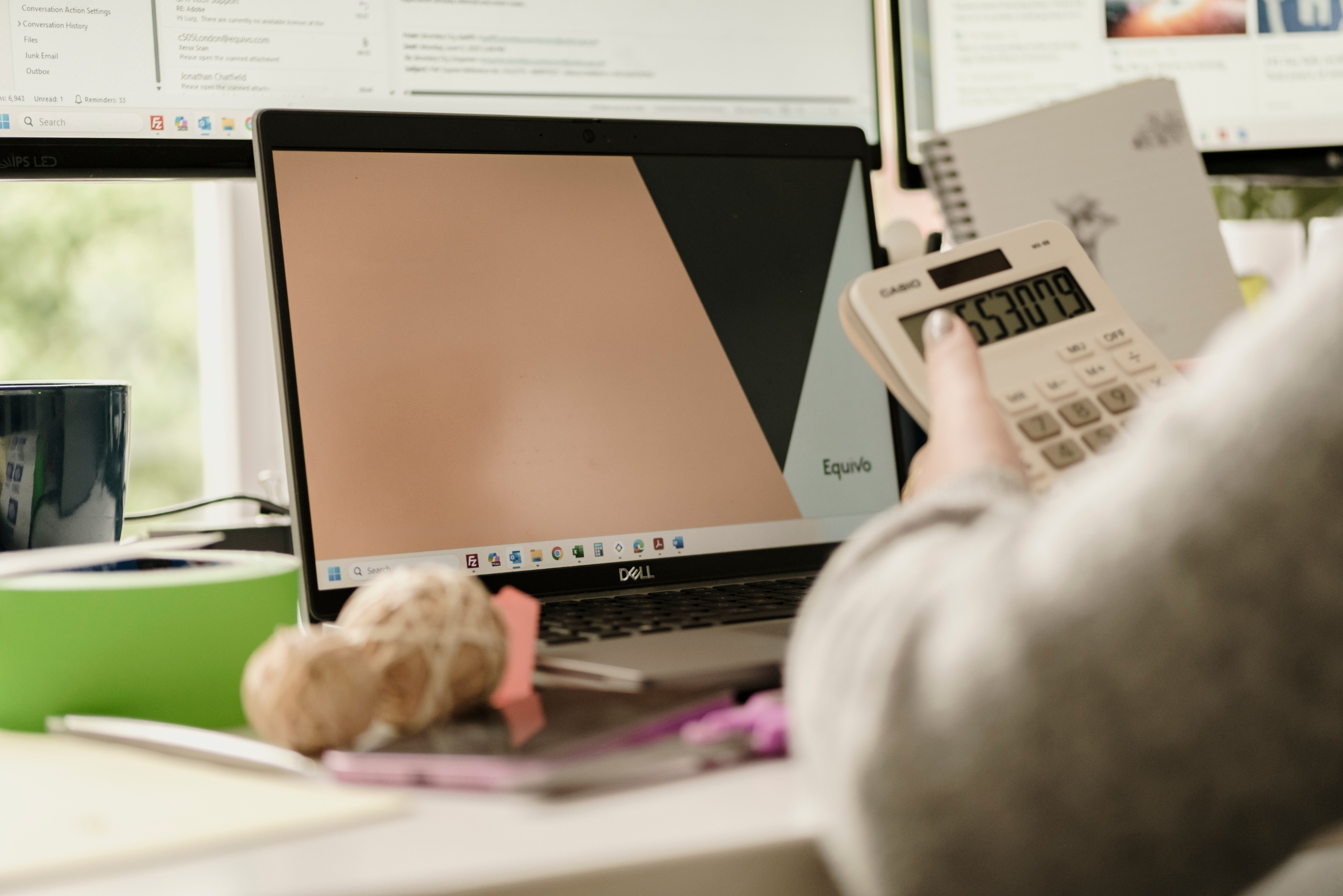 Person managing late-stage arrears recovery, reviewing documents with calculator and computer.